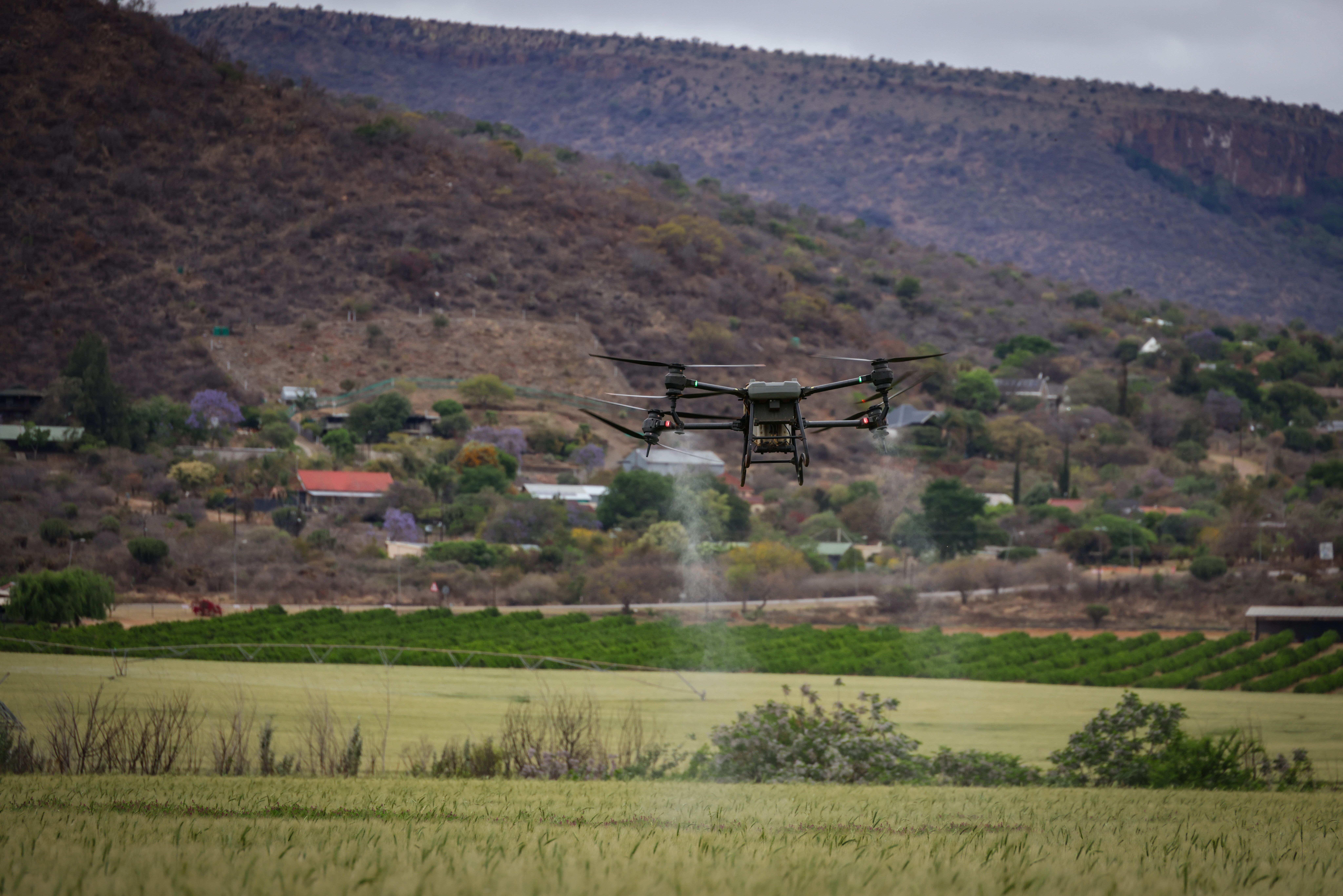 Agricultural drone spraying above a green field