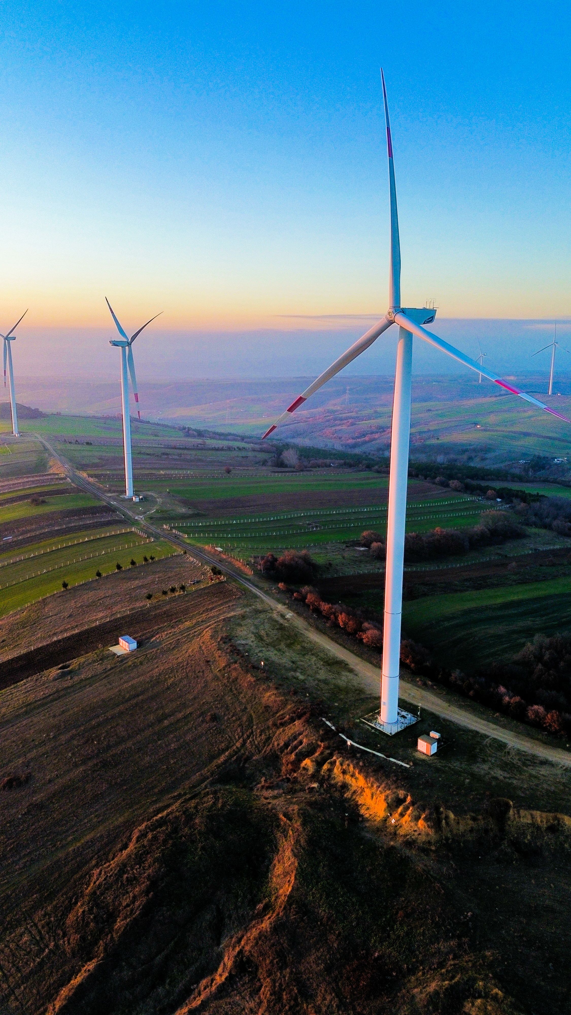 Wind turbines above farmland at sunset